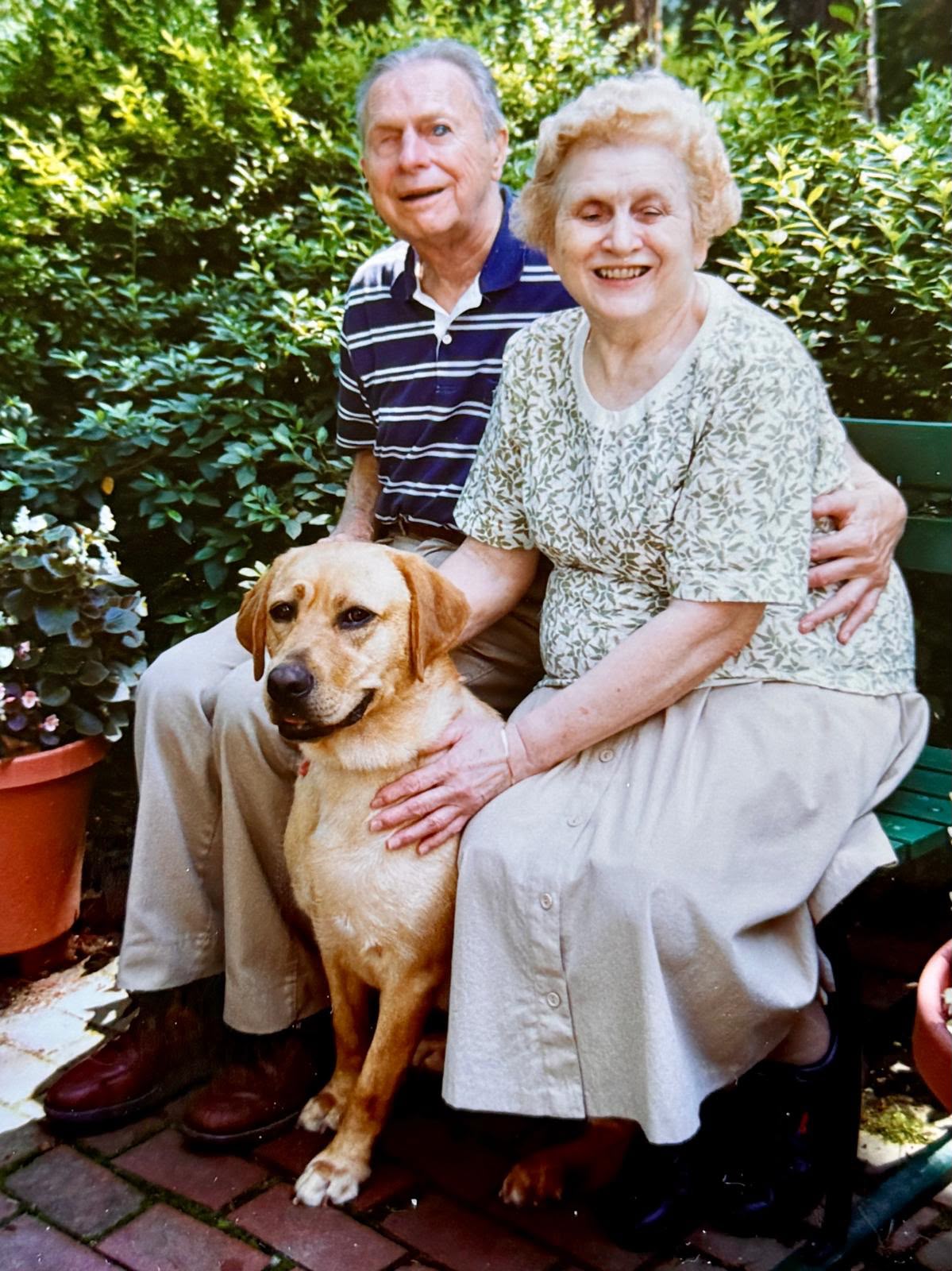 Mario and Jane seated outdoors with their dog Admiral